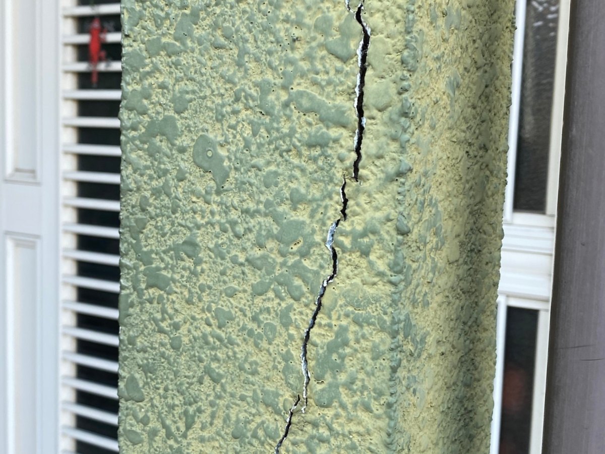 玄関ドアの横に縦に大きく入ったひび割れ（施工前）