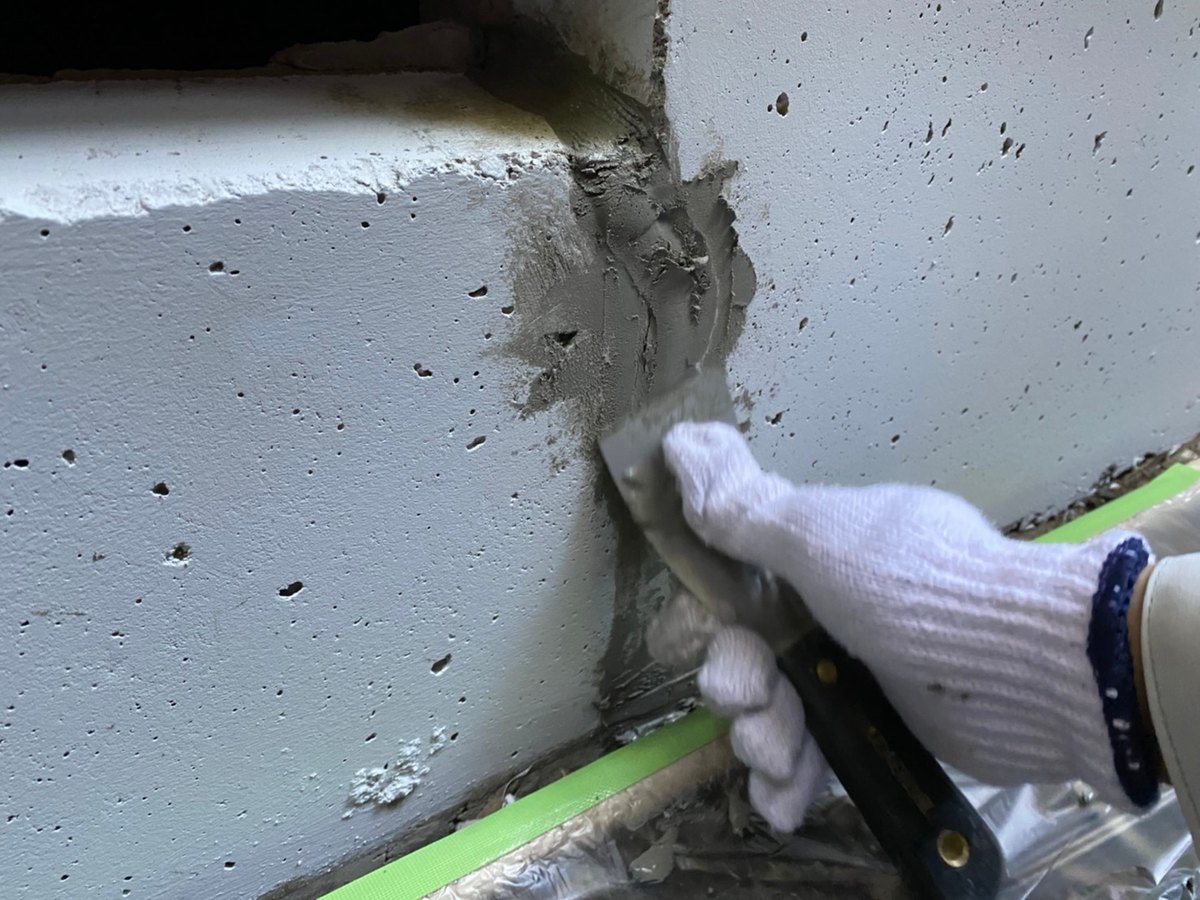 基礎のひび割れに詰めたモルタルを、ヘラで押さえているところ