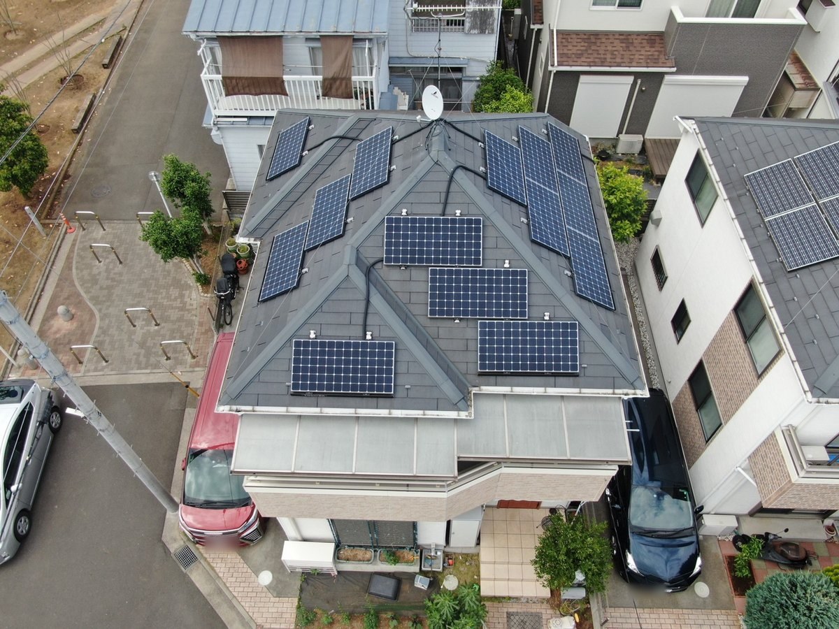 施工前の屋根（ドローン）。暗いグレーのスレートと太陽光パネル