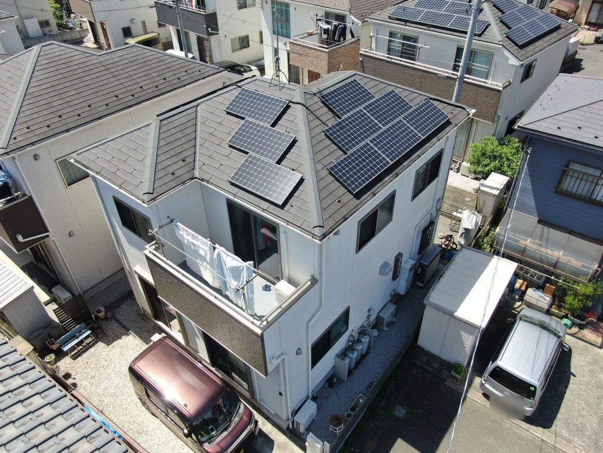 施工前の屋根と外壁（ドローン）。グレーのスレート屋根と太陽光パネル