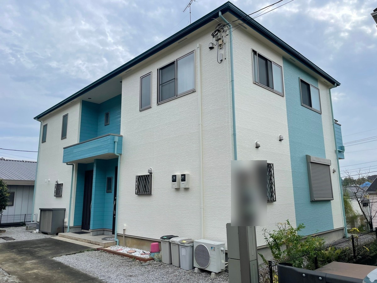 施工後の外観(正面)。白い外壁、水色の玄関まわりとバルコニーの外壁、青緑の縦のライン