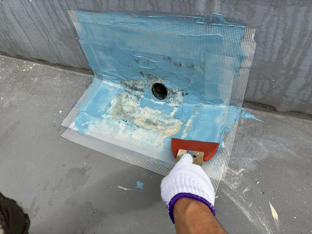 屋上の排水口まわりにメッシュを入れてウレタン防水を塗っているところ