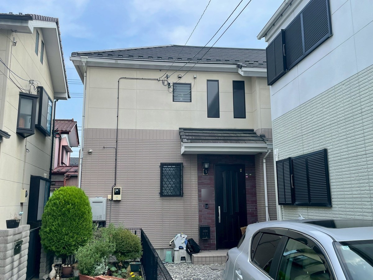 施工前の外観（正面・玄関側）。1階はピンクがかった茶、2階はベージュ