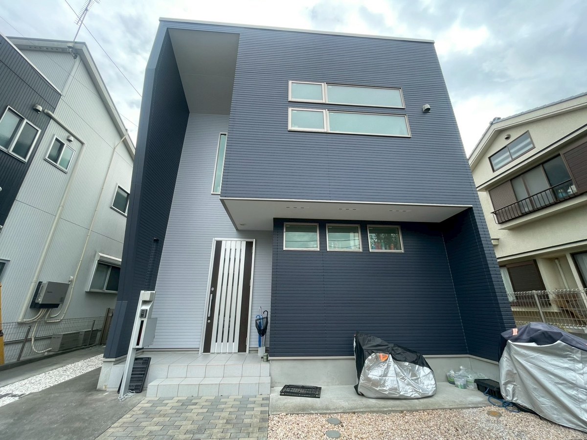 施工後の外観（正面・玄関側）。広い面は紺（75-30B）、玄関まわりの縦の面はライトグレー（75-70A）