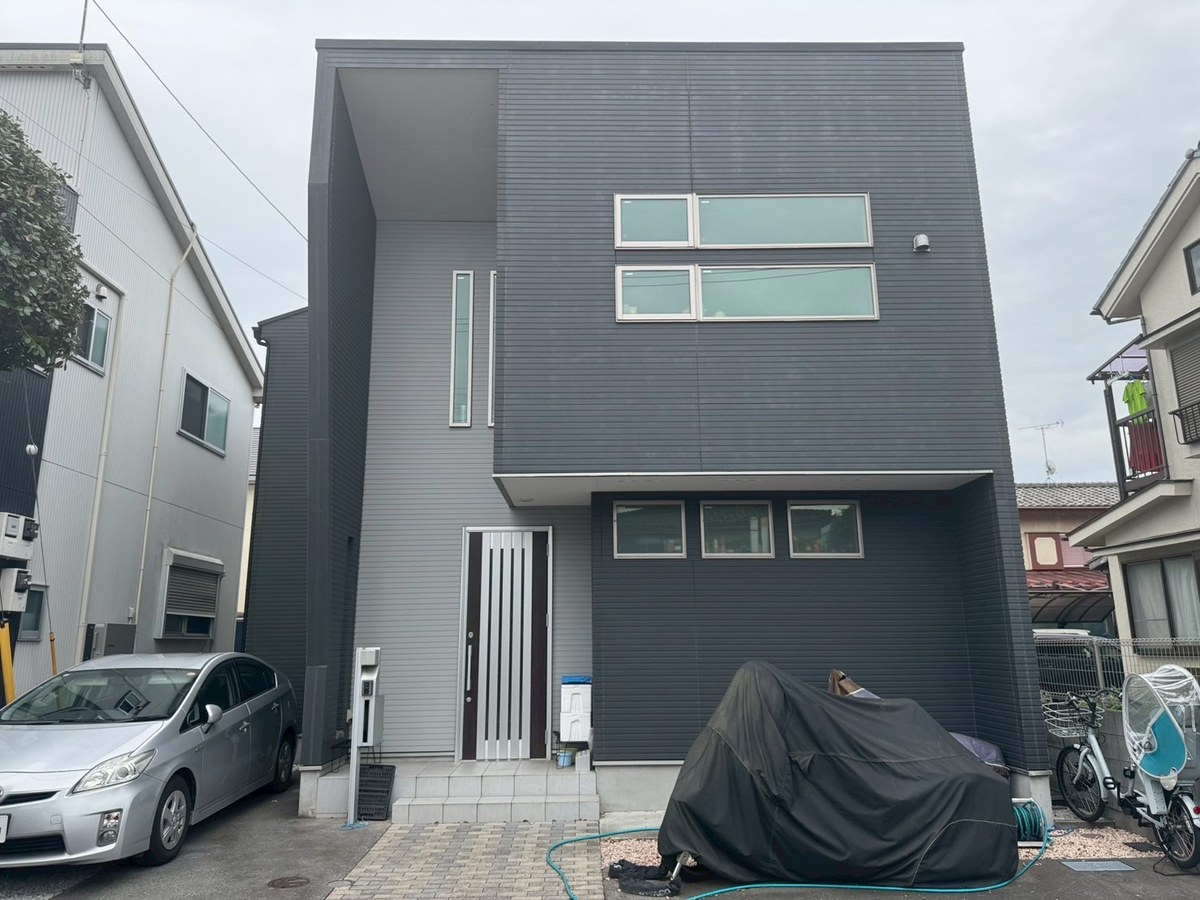 施工前の外観（正面・玄関側）。濃いグレーのサイディングと、玄関まわりの薄いグレーの縦の面