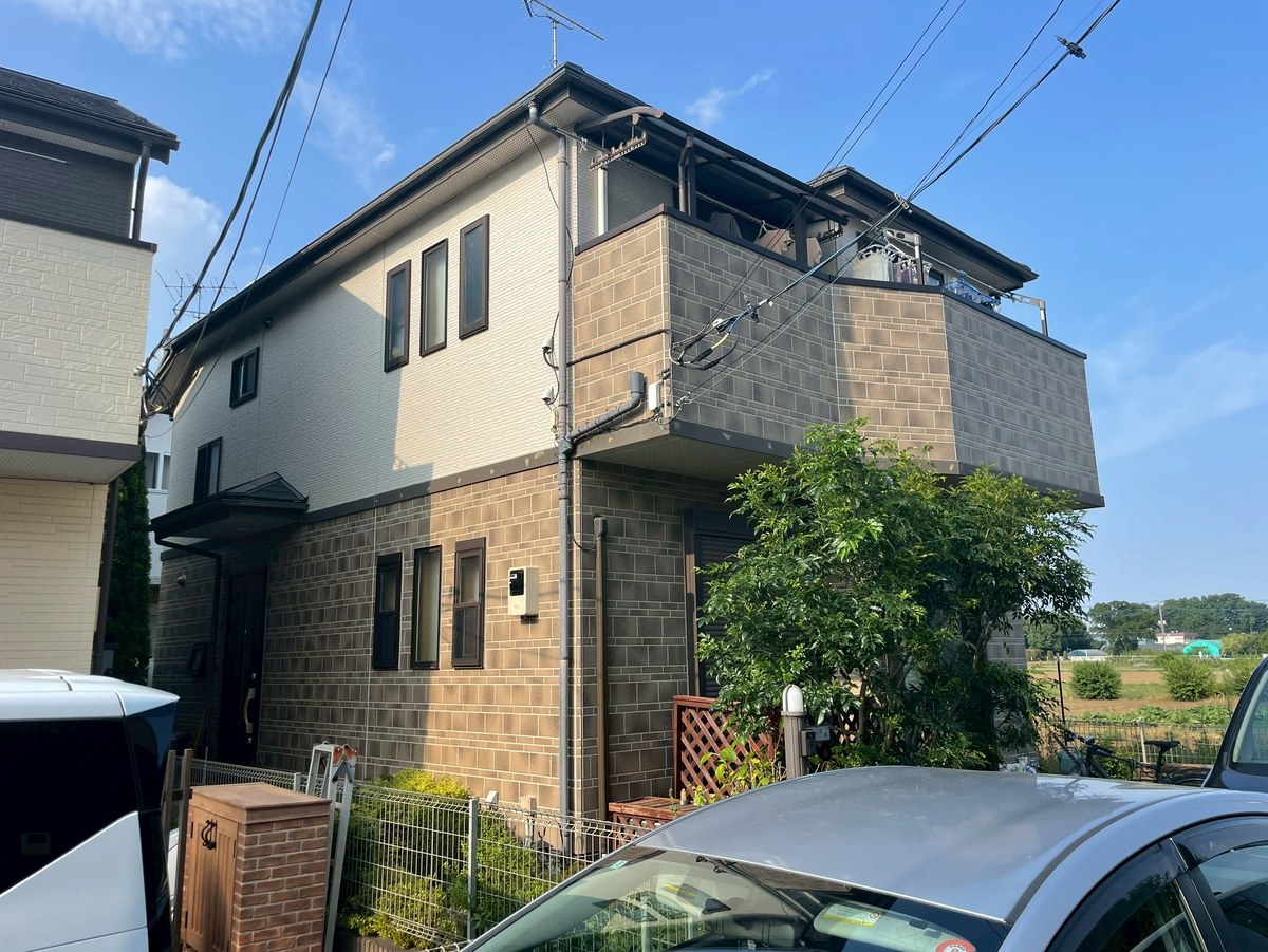 施工前の外観（道路側）。1階は茶色のレンガ調、2階は白系