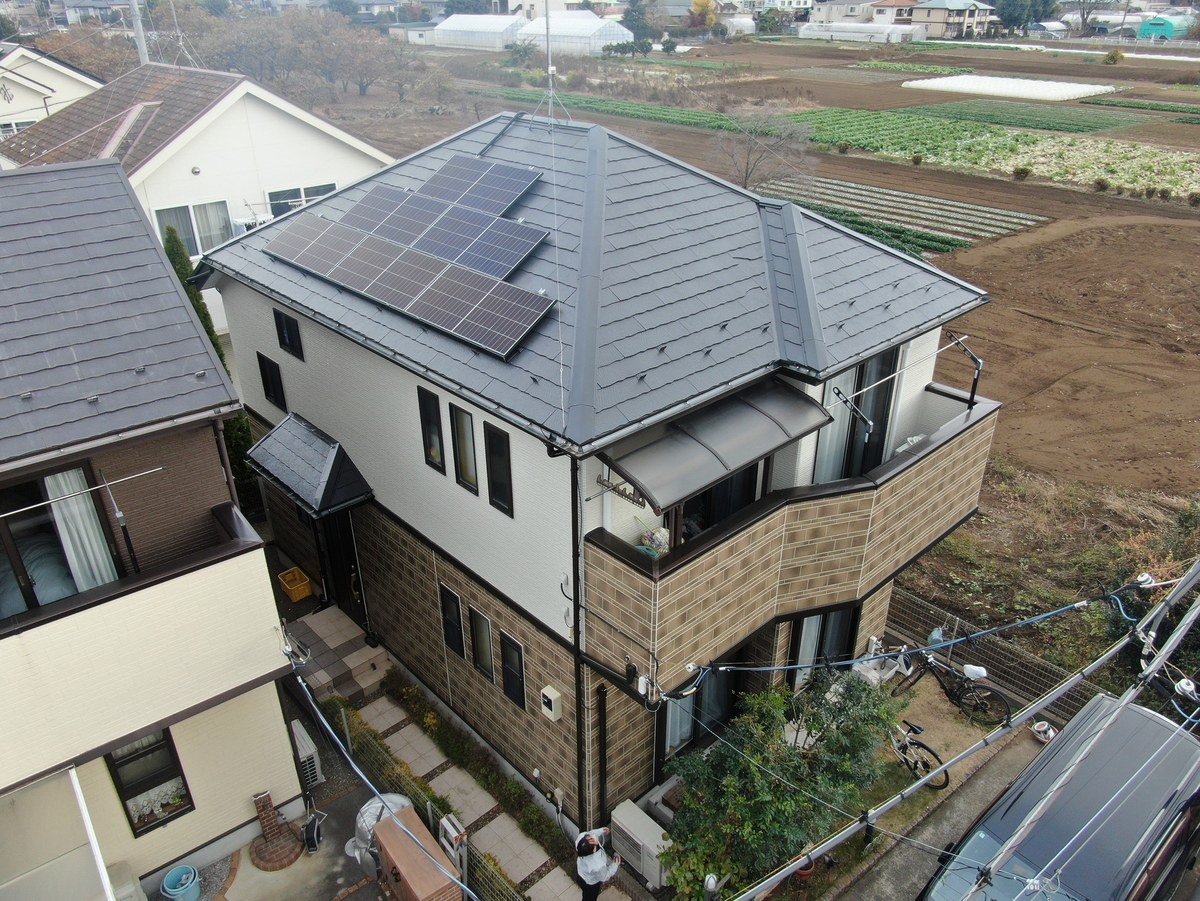 施工後の家全体（ドローン・斜め上から）。塗り替えた屋根に太陽光パネル