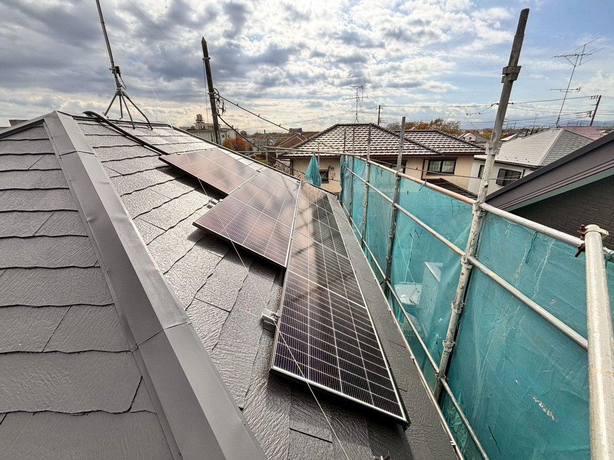 工事中の写真。塗り終えた屋根の上に太陽光パネルが載っている